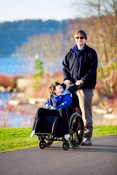 istock Father walking with disabled son in wheelchair 483836433