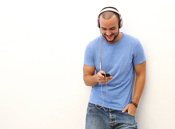 istock Smiling man standing with  mobile phone and headphones 483841126