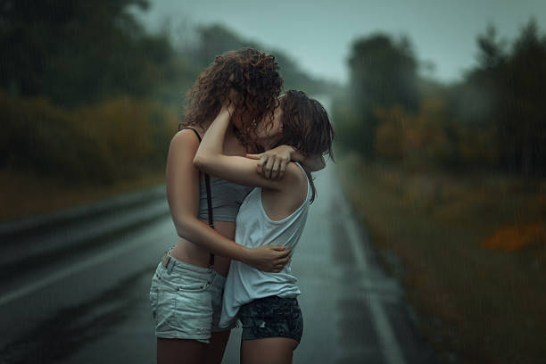 девушки, стоя в дождь на улице. - lesbian homosexual kissing homosexual couple стоковые фото и изображения