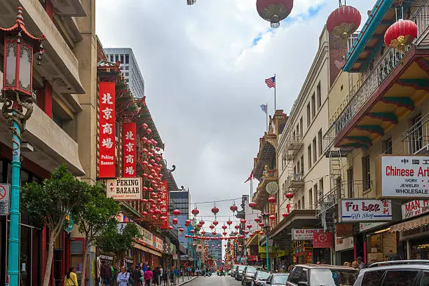 View of the main street of the chinatown district, traffic of cars and people in a cloudy day.