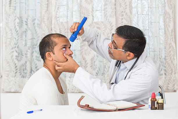 Mature Eye specialist examining a young patient. stock photo