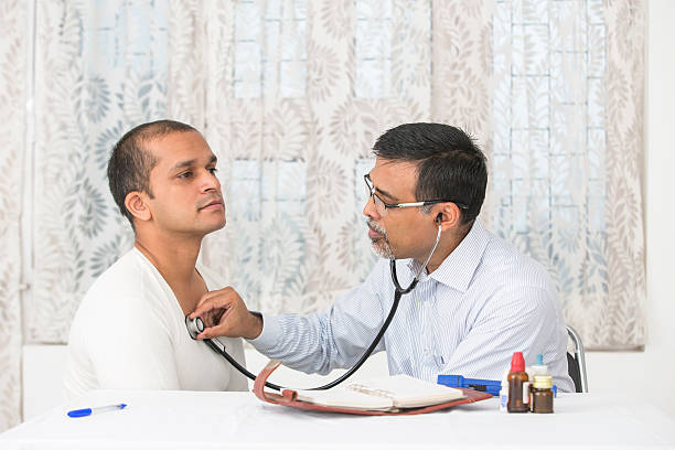 Mature Doctor examining a young patient with a stethoscope stock photo
