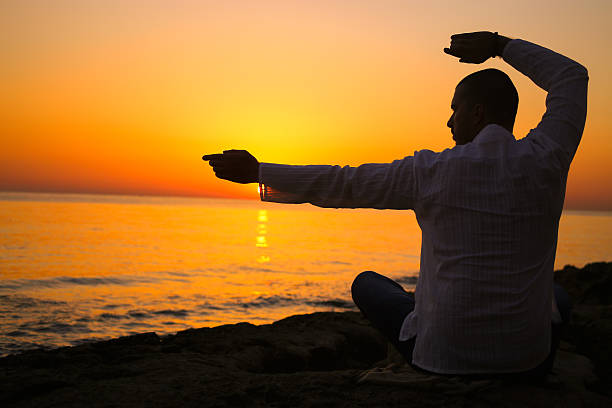 istock Young man practising yoga at the beach 483854098