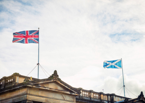 The union flag of Great Britain and the Scottish Saltire flying above a building in Edinburgh, Scotland's capital city.