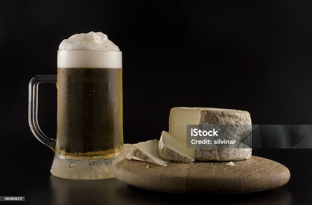 Foaming beer and cheese Foaming beer with artisanal goat cheese on wooden board Alcohol - Drink Stock Photo