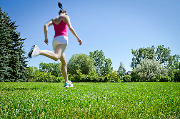 Young woman jumps into the camera frame while jogging through a park.