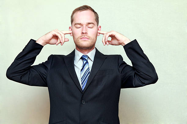 Man Putting Fingers in Ears Portrait of young handsome businessman with closed eyes and fingers in ears, not listening, isolated on gray ignoring photos stock pictures, royalty-free photos & images