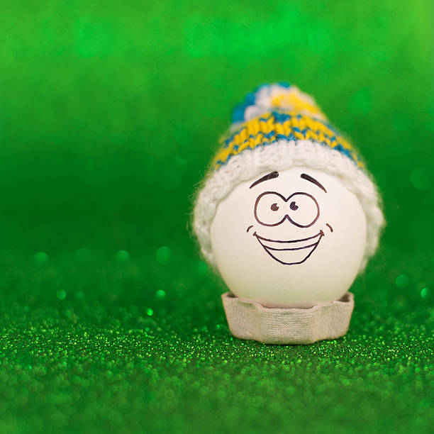 Huevo de pascua con rostro y sombrero sobre fondo verde brillante - foto de stock