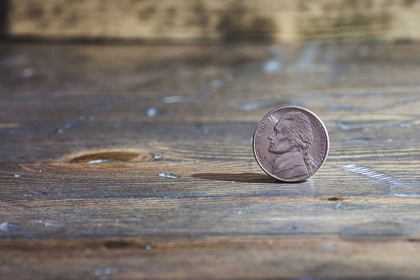 istock Nickel coin standing on end on wood table 483863133