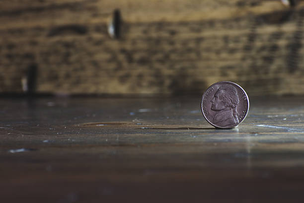 istock Nickel coin standing on end on wood table 483863135