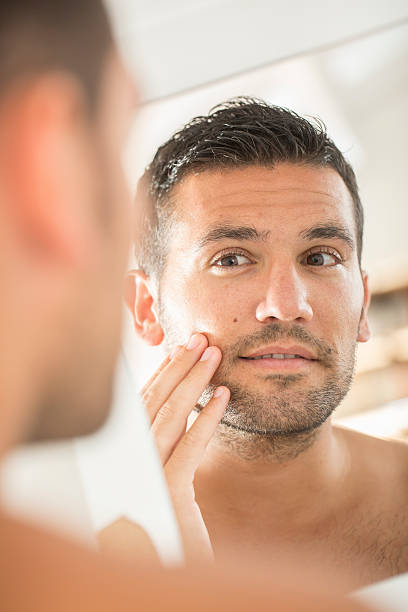 istock Young man in bathroom looking at mirror 483868636
