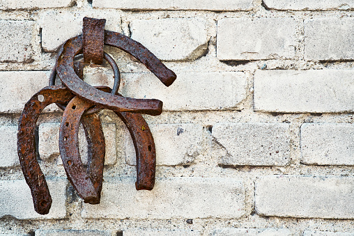 Three old rusty horsheshoe on white brick wall - sign of happiness