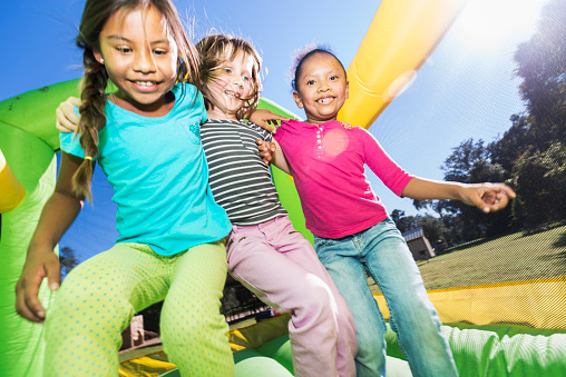 Multi-ethnic girls jumping together on bounce house