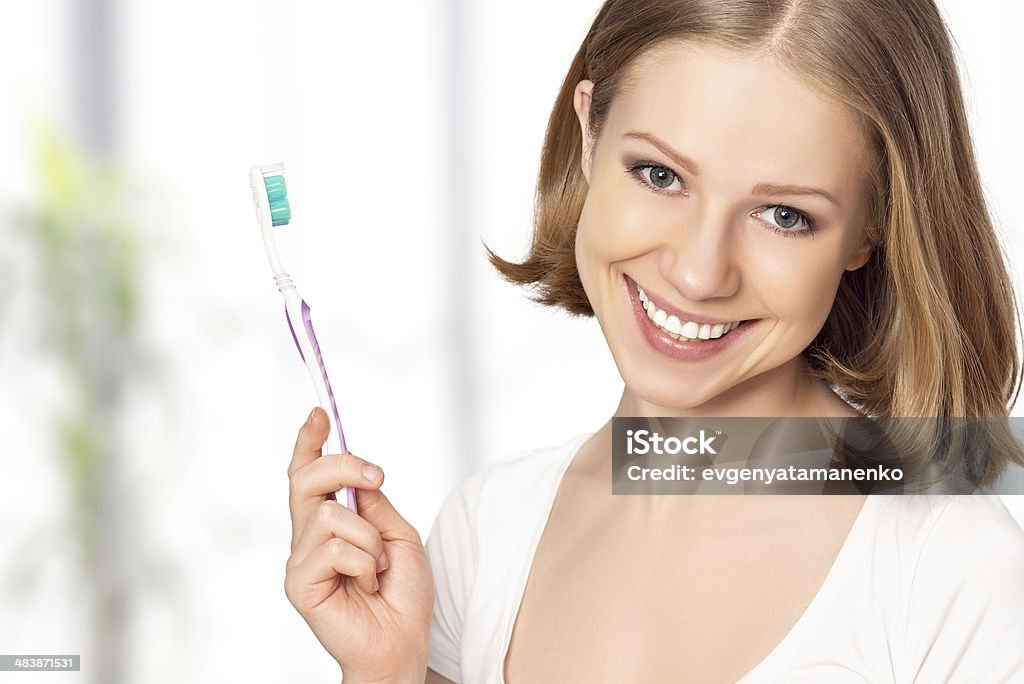 Szczęśliwa kobieta szczotkowanie zębów szczoteczką do zębów - Zbiór zdjęć royalty-free (Biały)