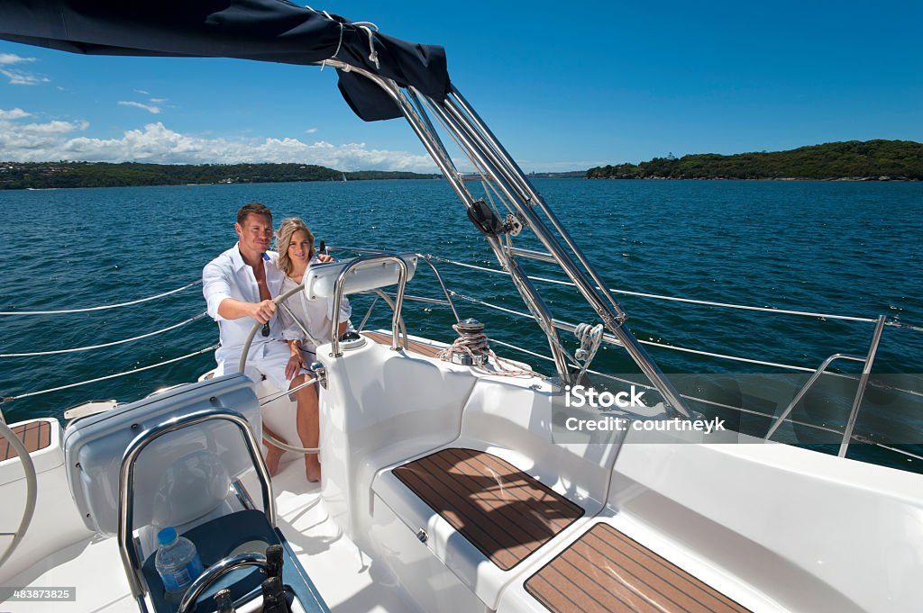 Casal feliz dirigindo um veleiro - Foto de stock de Iate - Embarcação de lazer royalty-free