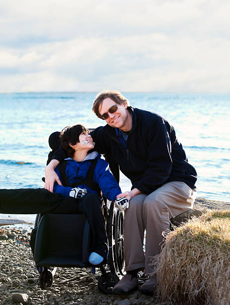 istock Father sitting with disabled son along lake shore 483873835
