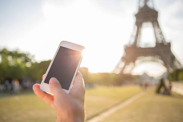 istock Woman photographing Eiffel tower using mobile phone 483874280