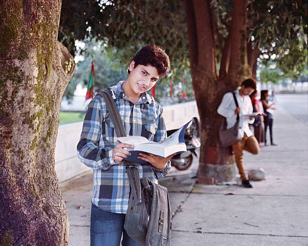 Indian / Asian college student studying while waiting in the campus parking.