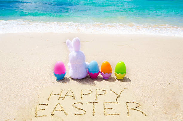 Sign Happy Easter with bunny and  eggs on the  beach stock photo
