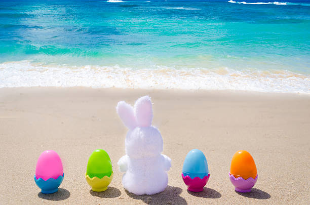 istock Easter bunny and color eggs on the beach 483874643