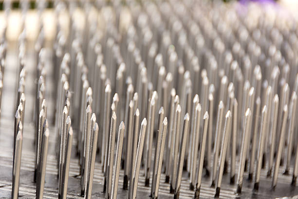 Bed of nails, side view closeup. Horizontal outdoor side view of shiny nails with pointy bits up. bed of nails stock pictures, royalty-free photos & images