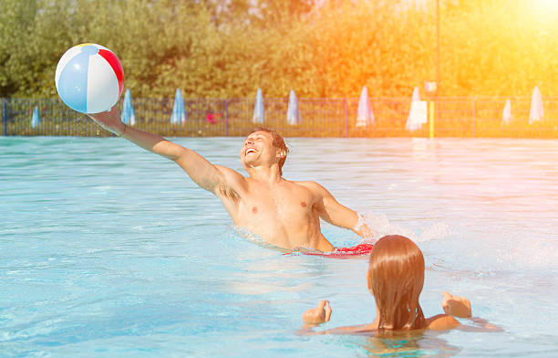 istock Young couple playing with beach ball on swimming pool 483875092