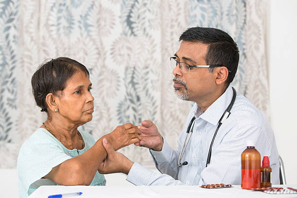 Mature Doctor examining a Rheumatoid Arthritis patient stock photo