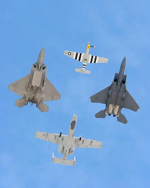 Flyover of four military aircraft: In front is a P-51 Mustang. On the right wing (our left) is an F-22 Raptor. On the left wing (our right) is an F-15 Eagle. And in the slot is an A-10 Warthog.