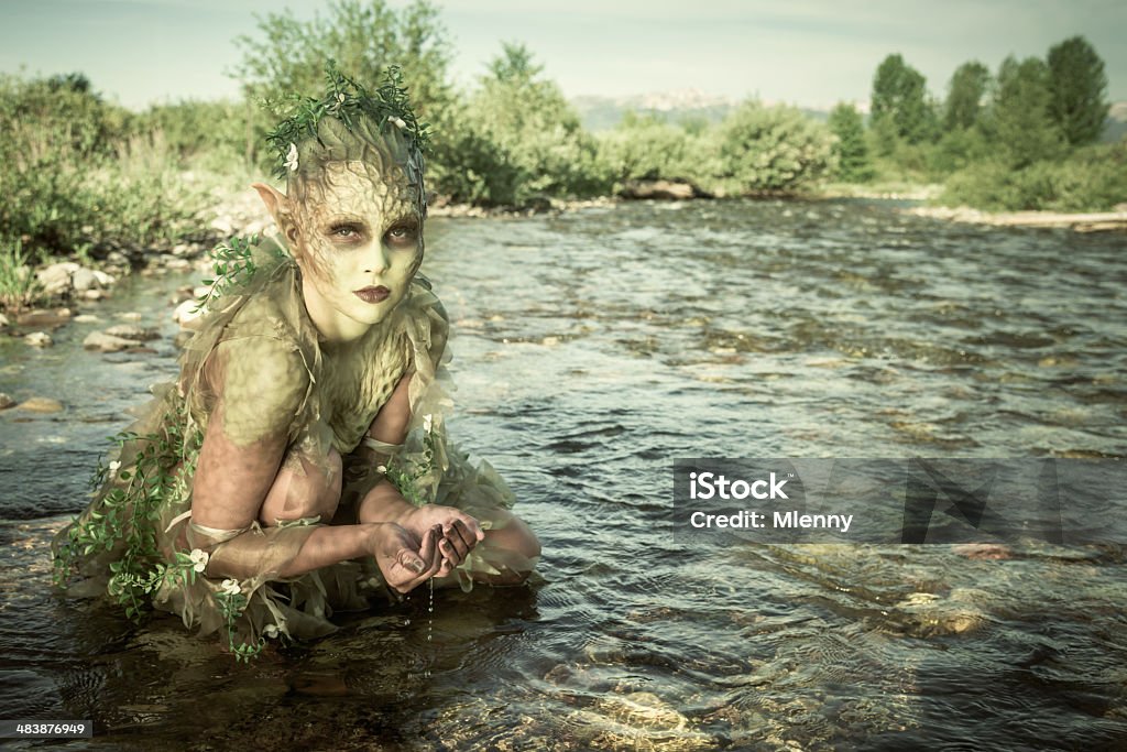 Water Nymph Water Nymph crouching in a river with clear water running through her hands. The Naiads or Potamides are a type of Water Nymphs of Greco-Roman Mythology. Elf Stock Photo