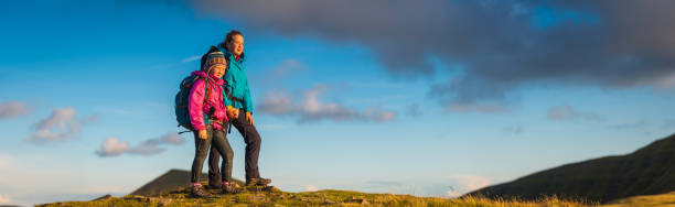istock Young hikers looking at sunset from mountain top wilderness panorama 483883038