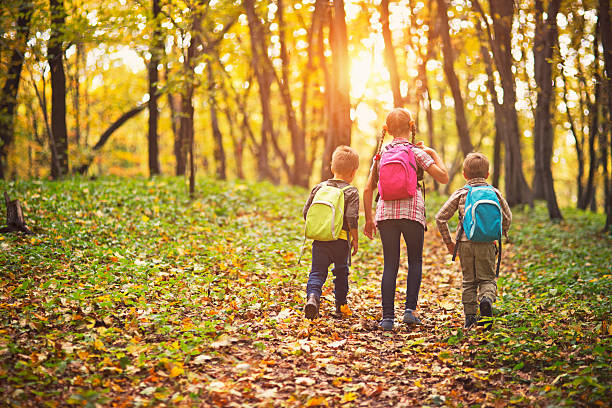 Kids with backpacks walking in autumn forest