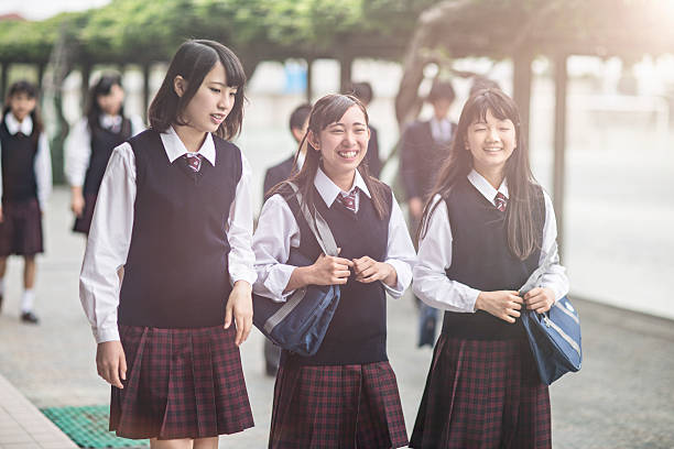 Japanese students walking outside the school yard, girls are talking very happy.