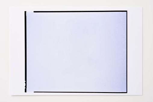 Close up of photographic paper with  blank 8x10inch photo frame isolated on white background.