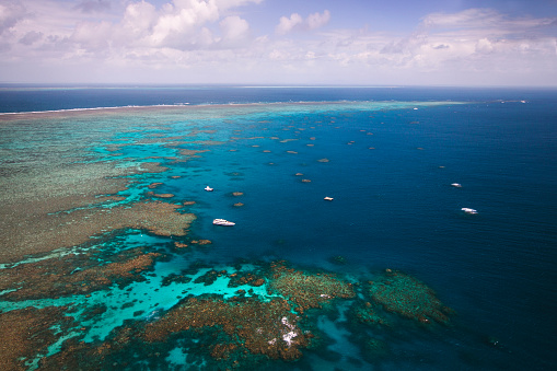 Aerial view of the great barrier reef with diving boats below.