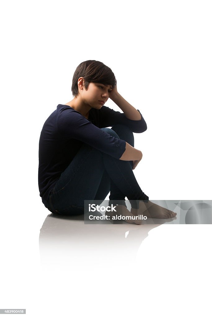 Side view of teenage girl sitting on floor and thinking Side view of teenage girl sitting on the floor and thinking isolated over white background Teenager Stock Photo