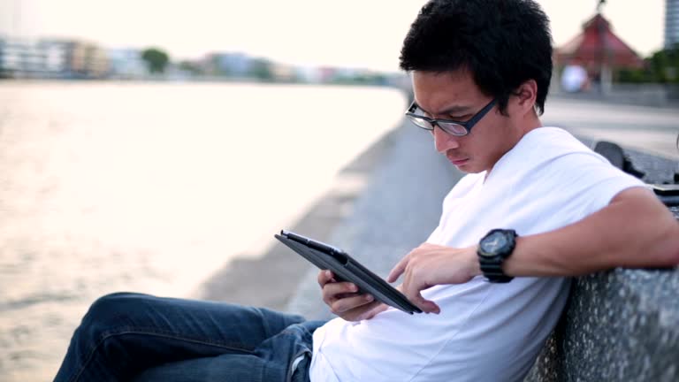 Man reading on his tablet at riverside