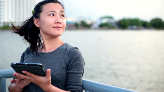 Woman reading on her tablet at riverside