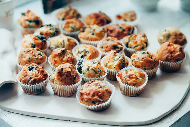 Mini fresh savory vegetable muffins with cheddar cheese, green onions, zucchini and spinach on the white dish