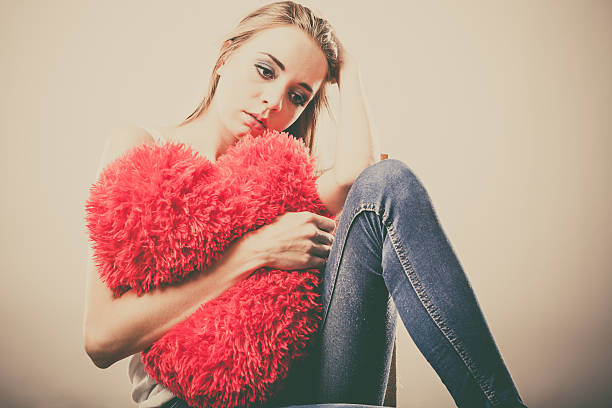 istock Sad unhappy woman holding red heart pillow 483904734