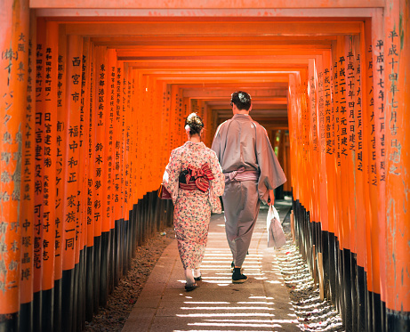 Kyoto, Japan - May 11, 2015: A couple wearing traditional Japanese kimonos, walking through a long series of inscribed Torii gates at Fushimi Inari-Taisha, on the outskirts of the ancient Japanese city of Kyoto.