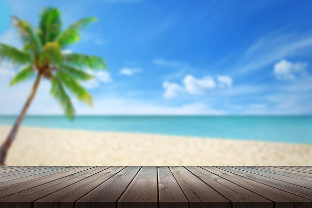 istock clean wood table beach and palm in background 483906286