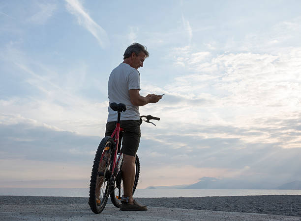 istock Man checks text from bicycle saddle, at beach 483913496