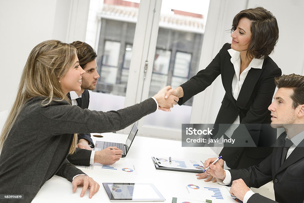 Business people shaking hands, finishing up a meeting Four business people shaking hands, finishing up a meeting Adult Stock Photo