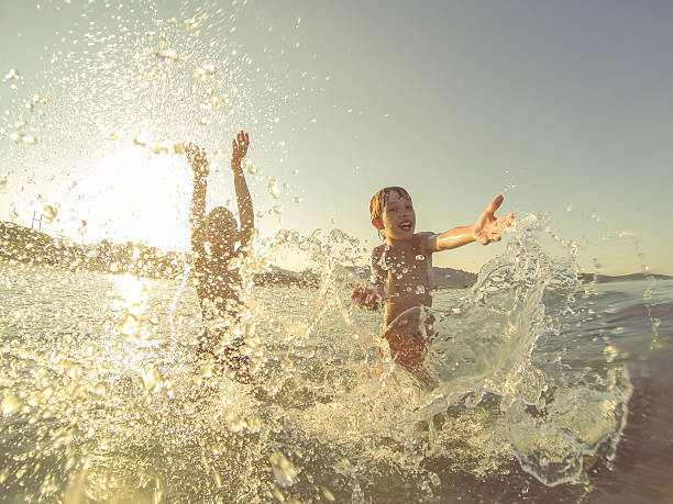 istock Boys having fun in the sea at sunset, splashin water 483916272