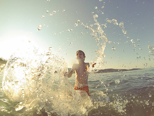istock Boy having fun in the sea at sunset, splashing water 483916276