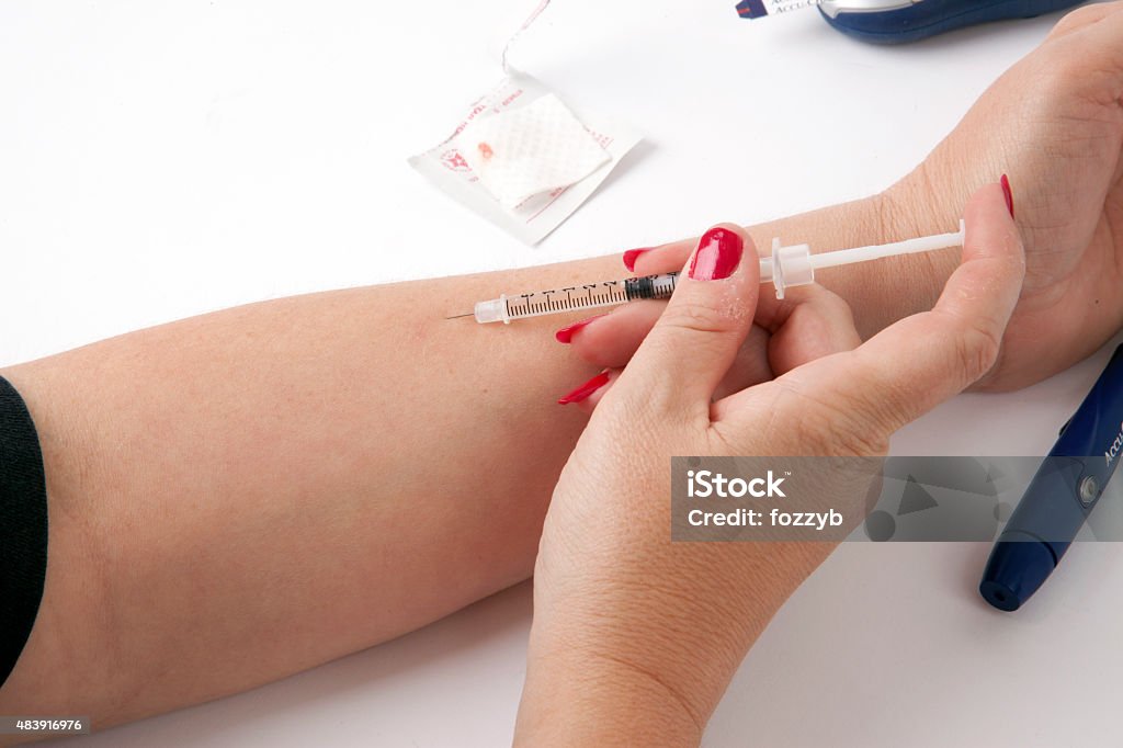 Diabetes Testing A woman injecting insulin into her arm. 2015 Stock Photo