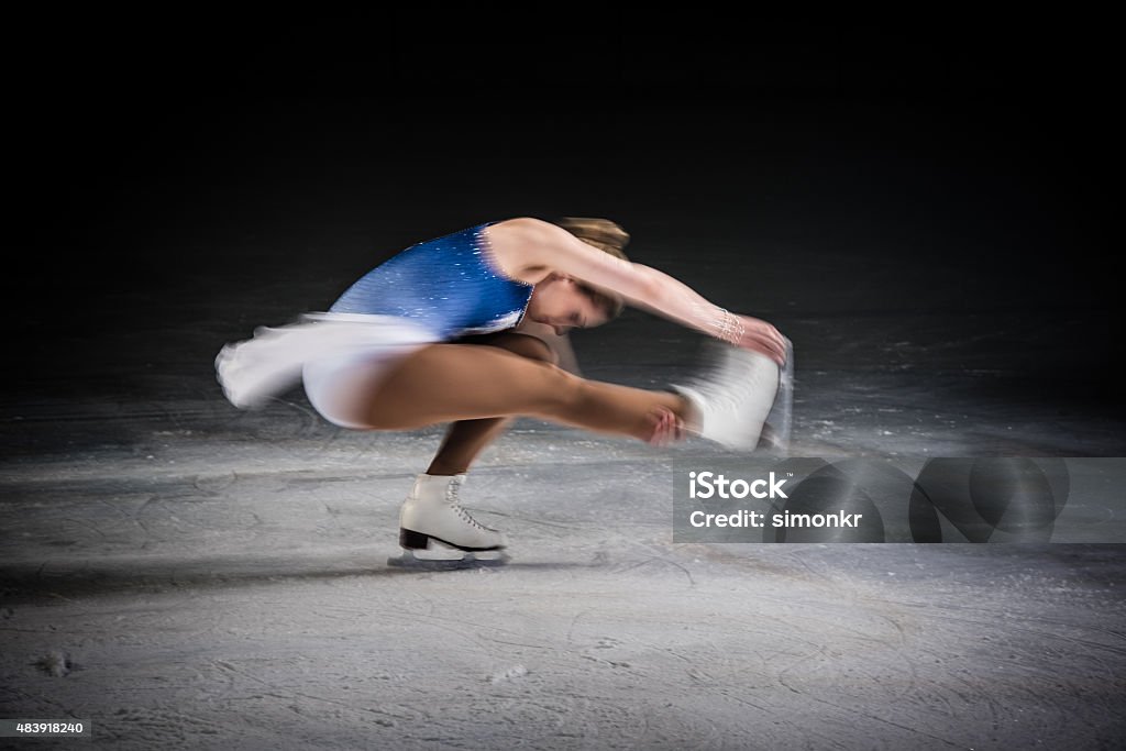 Young female figure skater performing Young female figure skater performing on ice rink, stretching her leg. Figure Skating Stock Photo