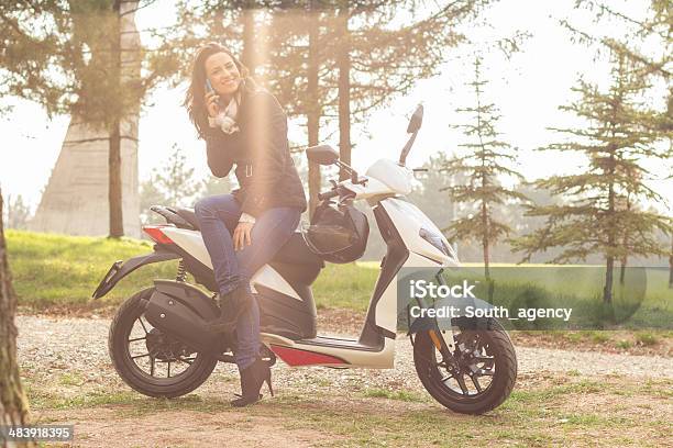 Woman Outdoors Leaning On Scooter Holding Her Mobile Phone Stock Photo - Download Image Now