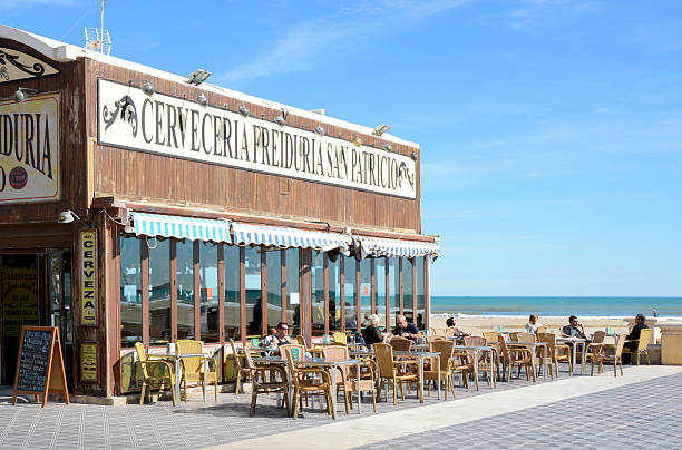 Valencia, Spain - February 26, 2015: Restaurant, cafe and bar on seafront promenade at Malvarossa beach in Valencia, Spain. With people sitting at tables