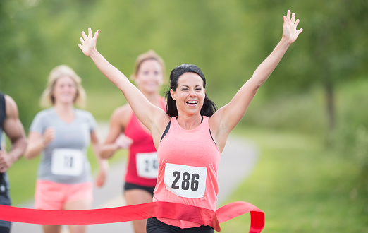 Adult female winning marathon race and going through finish line